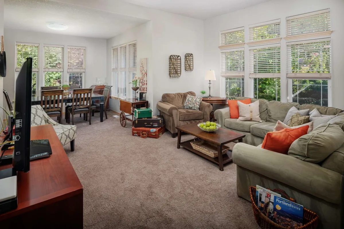 A bright, open-plan living and dining area adorned with comfortable sofas, a spacious dining table, and tasteful decorative accents. The room exudes warmth and offers ample space for families to gather, play games, or share a meal. Large windows fill the space with natural light, enhancing the inviting atmosphere.