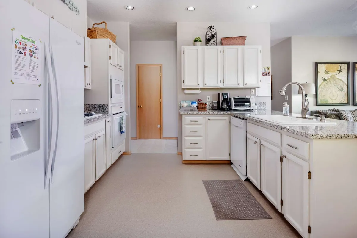 This image focuses on granite countertops and white cabinetry in a welcoming kitchen, with modern appliances and a practical layout for group meal preparation. The visible doorway hints at good flow between rooms, and the setup is ideal for both family cooking and entertaining guests.